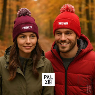 Bordeauxfarbene Mütze mit weißer Schrift und Bommel, aus Wolle oder Acryl-Mischung.