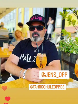 Ein alkoholischer Cocktail, serviert in einem Weinglas mit zwei Strohhalmen und einer Orangenscheibe.