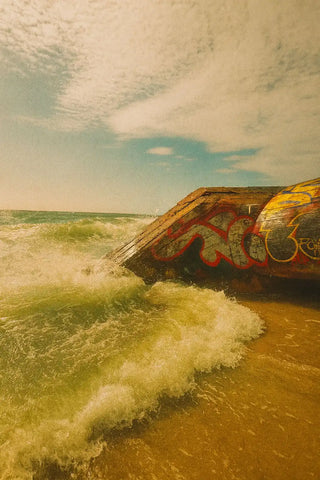 Ein Betonkutter, der von Graffiti bedeckt ist und von Meereswellen getroffen wird.