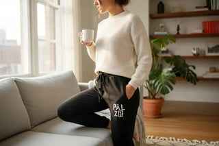 Cremefarbener Stricksweater mit schwarzen Leggings mit ’palzig’-Design und weißem Text.