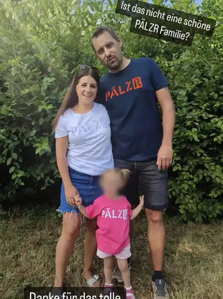 Eine Familie von drei Personen trägt passende „PÄLZR“-Shirts.