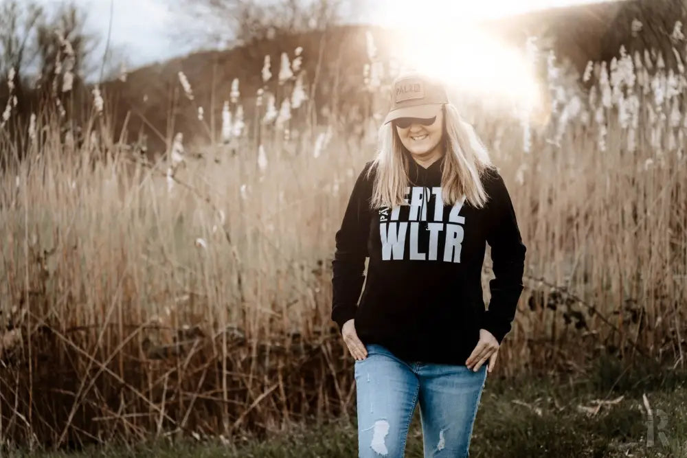 Schwarzes ’krtz wltr’ Hoodie mit abgetragenen Denim-Jeans und einer beigen Kappe.