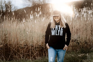 Schwarzes ’krtz wltr’ Hoodie mit abgetragenen Denim-Jeans und einer beigen Kappe.