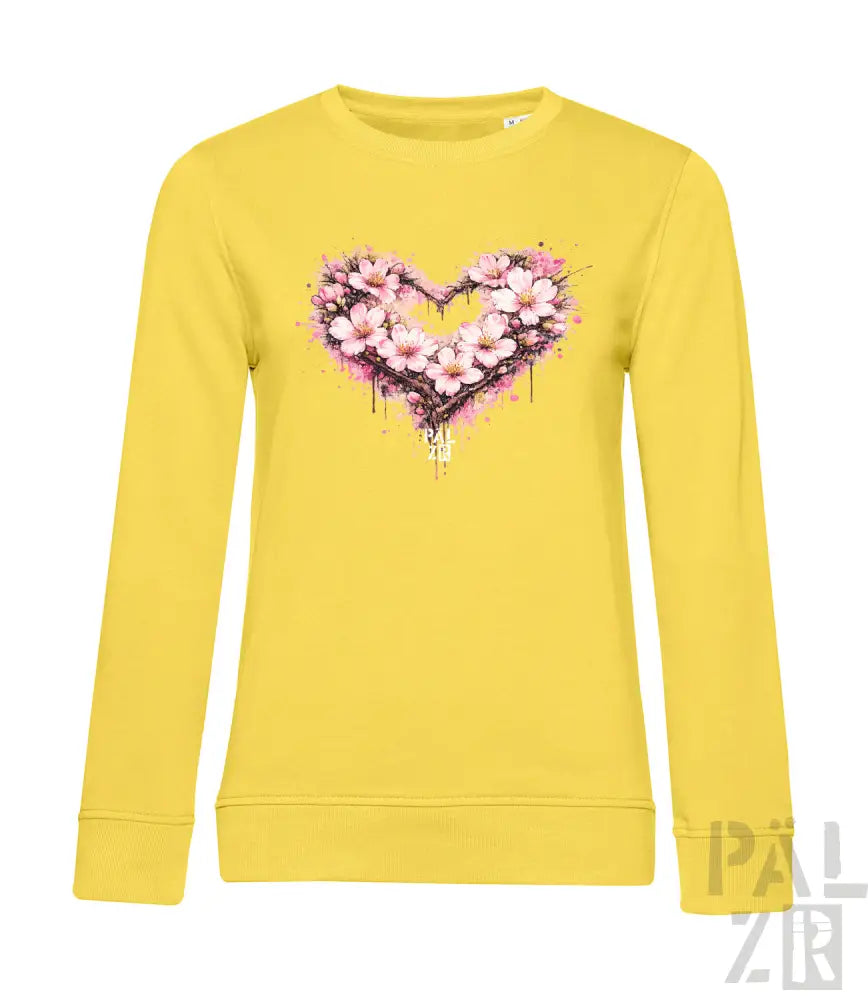Ein lebendiges gelbes Langarm-Sweatshirt mit einem herzförmigen Blumenmuster aus pinken Blüten und Spritzfarbeffekten.