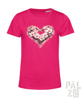 Ein lebhaftes rosa Damen-T-Shirt mit einem herzförmigen Blumenmuster, das zarte Blüten und Spritzeffekte aufweist.