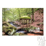 Holzpergola mit moosbedecktem Dach und rustikalem Design, gelegen an einem Wald bach.