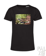 Schwarzes T-Shirt mit Waldszenen-Design, das eine kleine Holzkonstruktion und einen grünen Schirm zeigt.