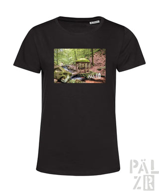Schwarzes T-Shirt mit Waldszenen-Design, das eine kleine Holzkonstruktion und einen grünen Schirm zeigt.