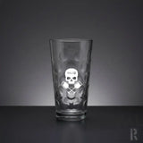 Klares Glas-Pint-Glas mit einer texturierten, eingedrückten Oberfläche und einem geätzten weißen Totenkopf-Logo, darunter gekreuzte Ruder.
