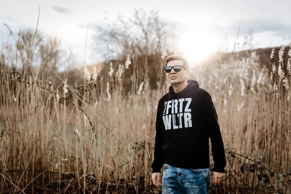 Schwarze Kapuzenjacke mit weißem Text ’frtz wltr’ und Sonnenbrille.