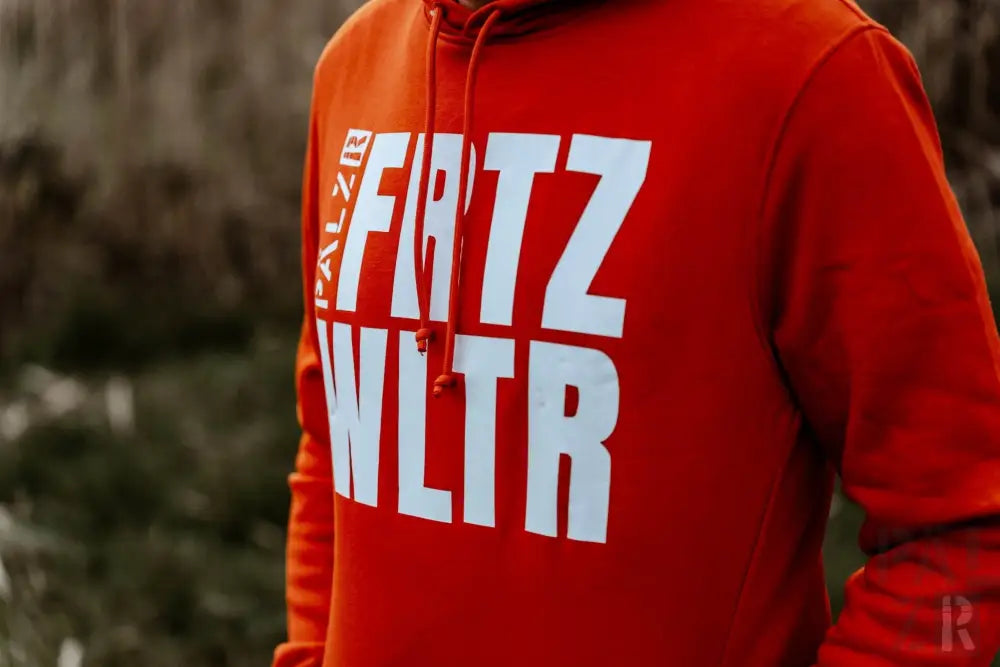 Roter Hoodie mit weißem Text ’frtz wltr’ und orangenen Kordeln.