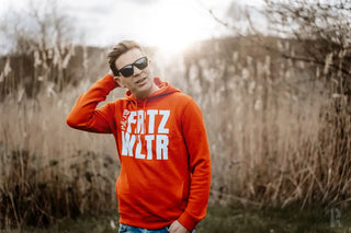 Orangefarbene Kapuzenjacke mit dem Text ’fatz wltr’ und Grafikdesign.