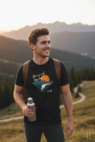 Schwarzes T-Shirt mit einem grafischen Druck einer orangenen Sonne, die über Berge untergeht, und dem deutschen Satz ’du wo ich her bin’ in weißer Schrift, mit einem kleinen Logo darunter.