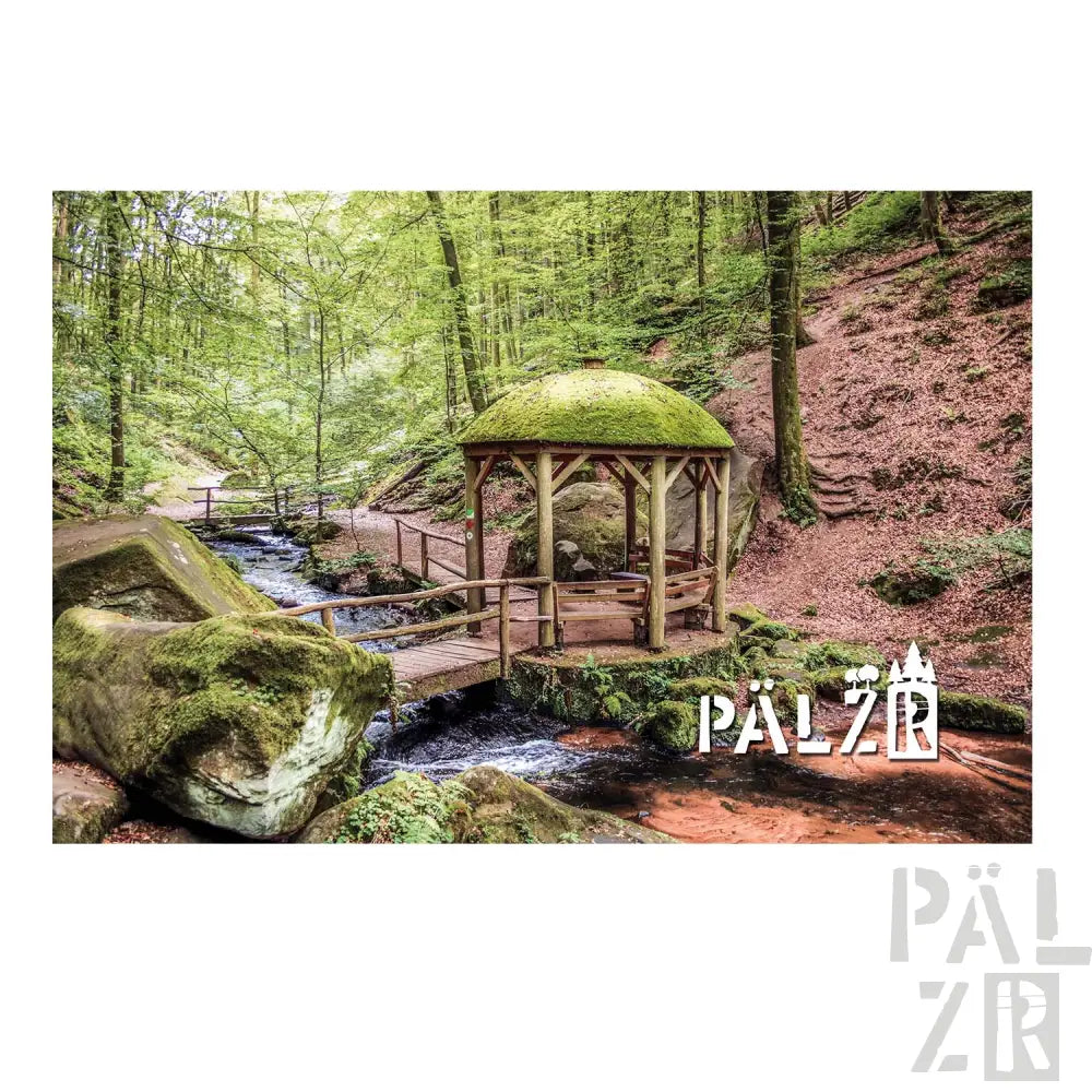 Holzpergola mit moosbedecktem Dach und rustikalem Design, gelegen an einem Wald bach.