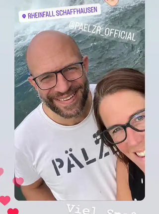 Ein Paar mit Brille, das smiling in die Kamera schaut.