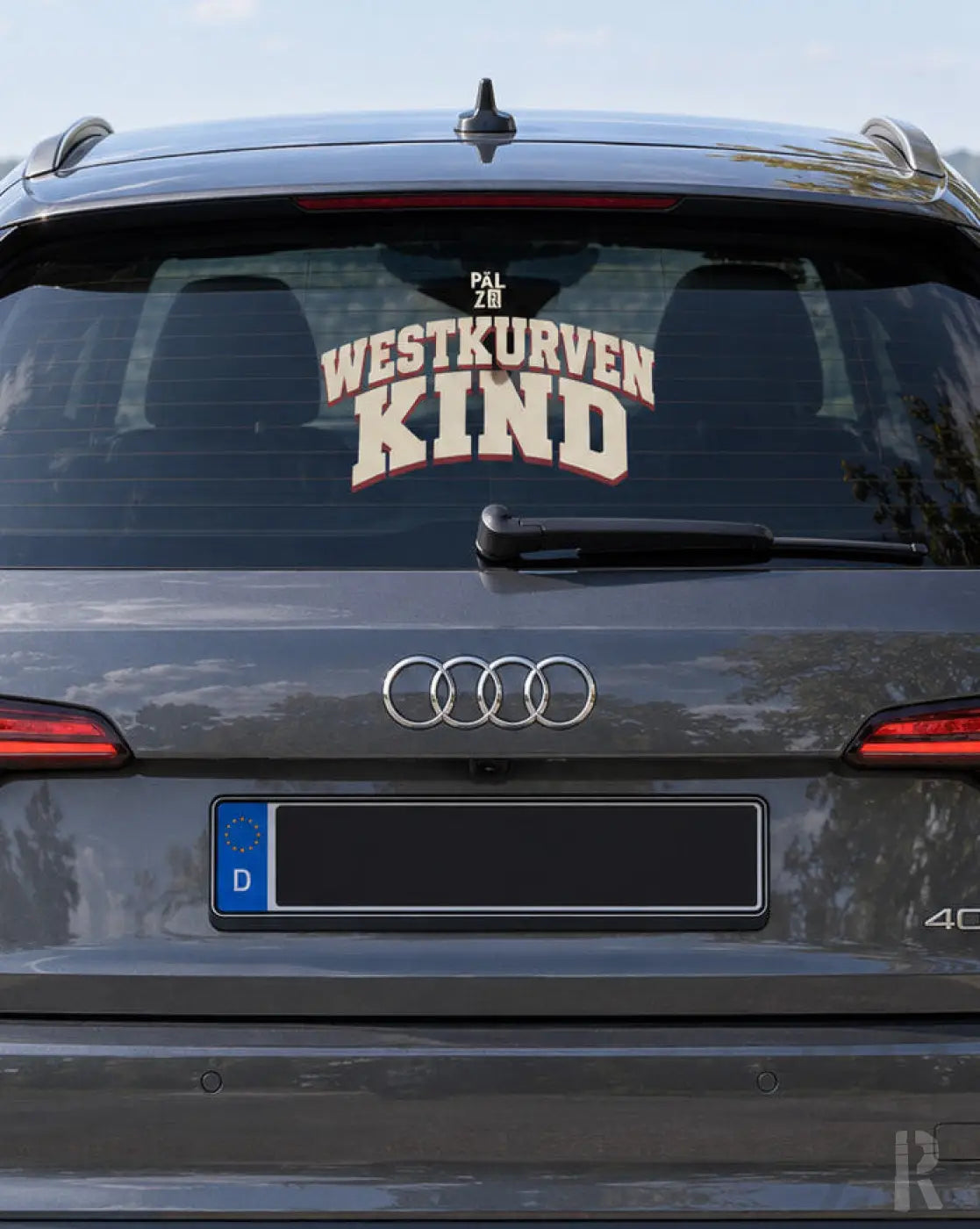 Rückseite eines dunkelgrauen audi suv mit weiß-rotem westkurven kind autoaufkleber von päłzr