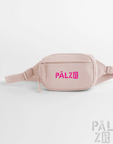 Ein blush pink palzr studio bag mit einem auffälligen magenta logo und verstellbarem riemen