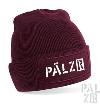 Bordeaux-farbene Rippenmütze mit weißem ’pälzr’-Logo-Patch auf der Vorderseite.