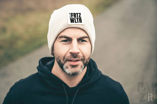 Weiße Beanie mit schwarzem Text ’frtz wltr’ und Logo, wahrscheinlich aus Wolle oder Acryl.