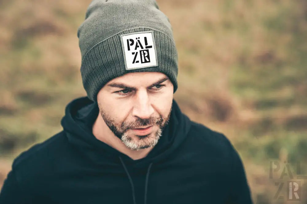 Graue Mütze mit ‚pälzer‘-Logo und schwarzem Hoodie.