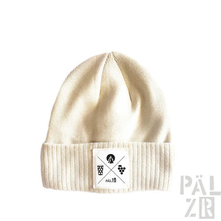 Cremeweiße gerippte Mütze mit weißem Patch, der gekreuzte Icons und Text zeigt.