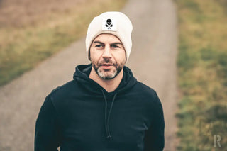 Weiße Schädelmütze mit schwarzem Logo und Materialtextur.