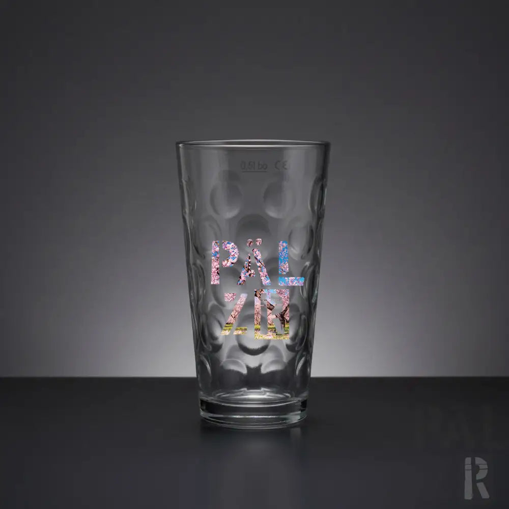 Klares Glas-Pint-Glas mit texturierter, blasenartiger Oberfläche und farbenfroher ’pal zir’-Beschriftung in einem Mosaik-Stil-Design.
