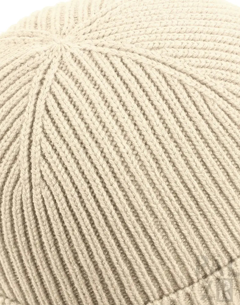 Cremeweiße Strickmütze mit gerippter Textur und leicht gefaltetem Rand.