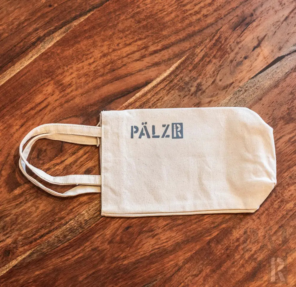 Cremeweiße Umhängetasche mit ’pälzr’-Logo in Dunkelblau auf der Vorderseite.