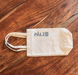 Cremeweiße Umhängetasche mit ’pälzr’-Logo in Dunkelblau auf der Vorderseite.