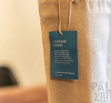 Fairtrade-Baumwolltasche aus braunem Canvas mit türkisfarbenem Etikett und Schnurverschluss.