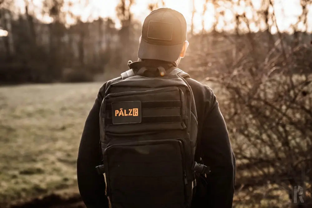 Schwarzer taktischer Rucksack mit orangem Logo und Gurten, pálz Marke.