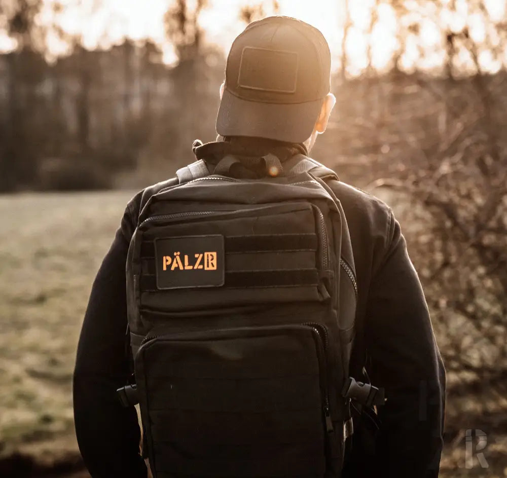 Schwarzer taktischer Rucksack mit orangem Logo und Patch, pälzr Marke.