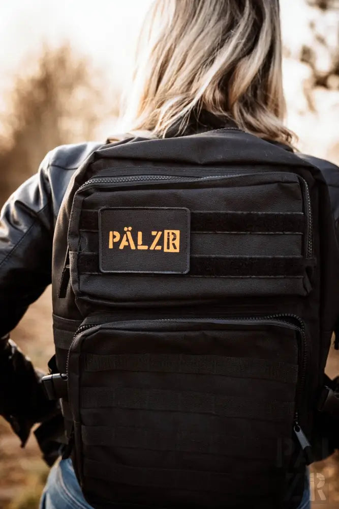 Schwarzer taktischer Rucksack mit goldenem Logo und mehreren Taschen.