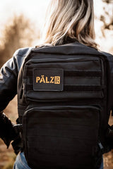 Schwarzer taktischer Rucksack mit goldenem Logo und mehreren Taschen.