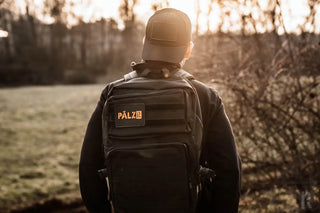 Schwarzer taktischer Rucksack mit orangem Logo und Gurten, pálz Marke.