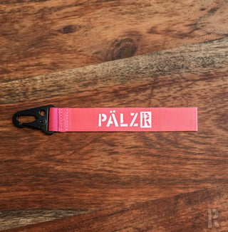 Rosa Palzer-Lanyard mit schwarzer Metallklemme und weißem Logo.