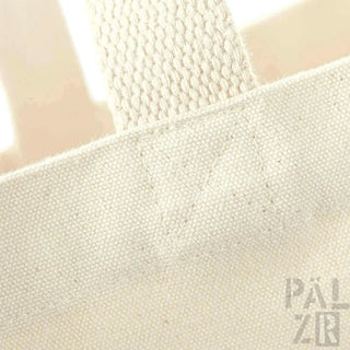 Cremeweiße Leinwand-Tasche mit gewebten Griffen und ’palzir’-Branding.