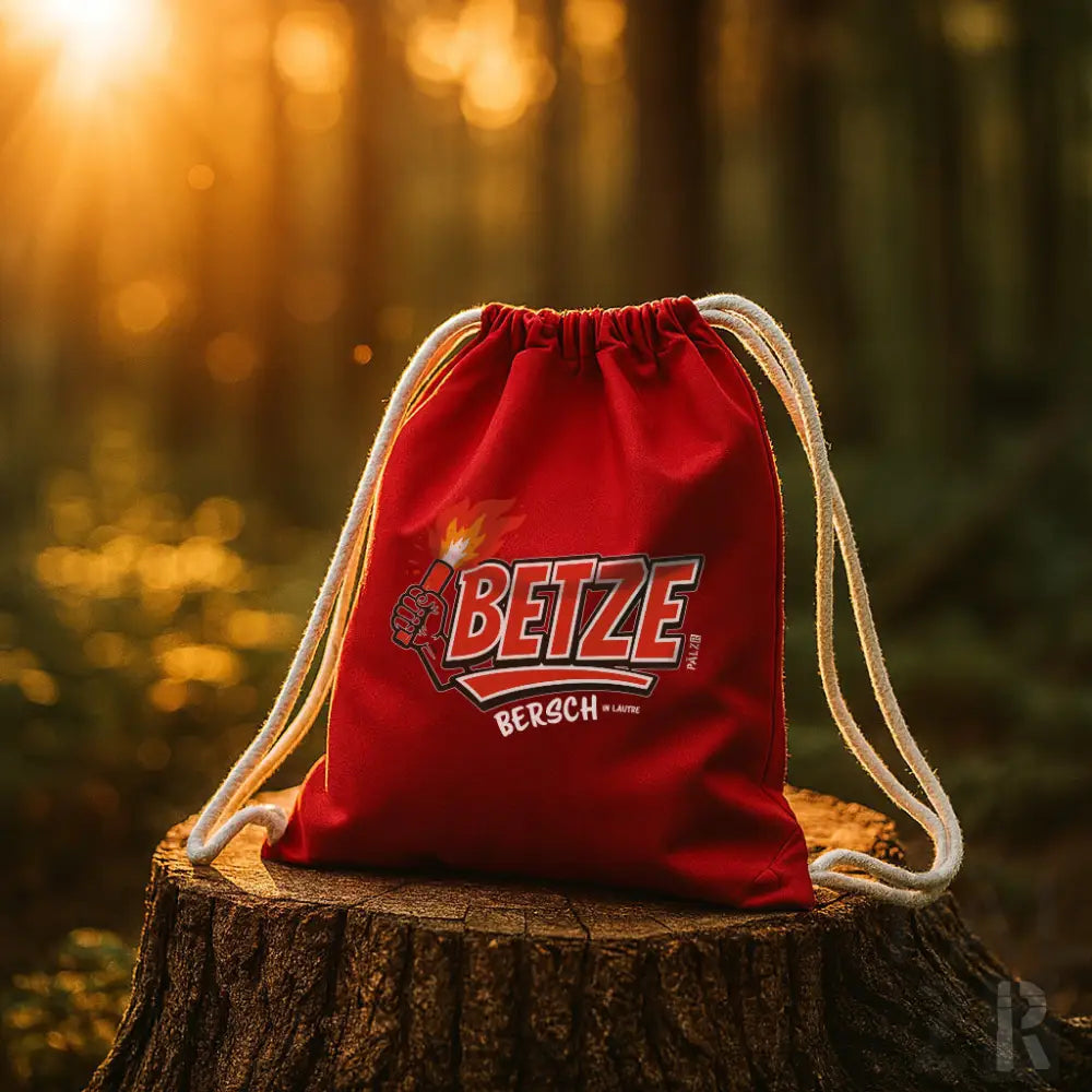 Roter Rucksack mit Kordelzug, Logo ’betze bersch’ und Sonnenstrahldesign.