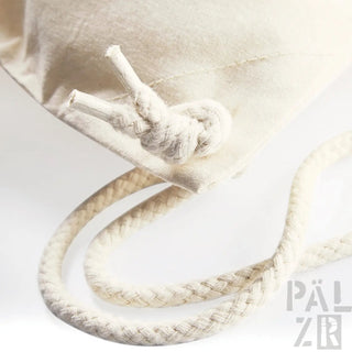 Cremefarbene Seilzugtasche mit Knotenschluss und gewebtem Textil.