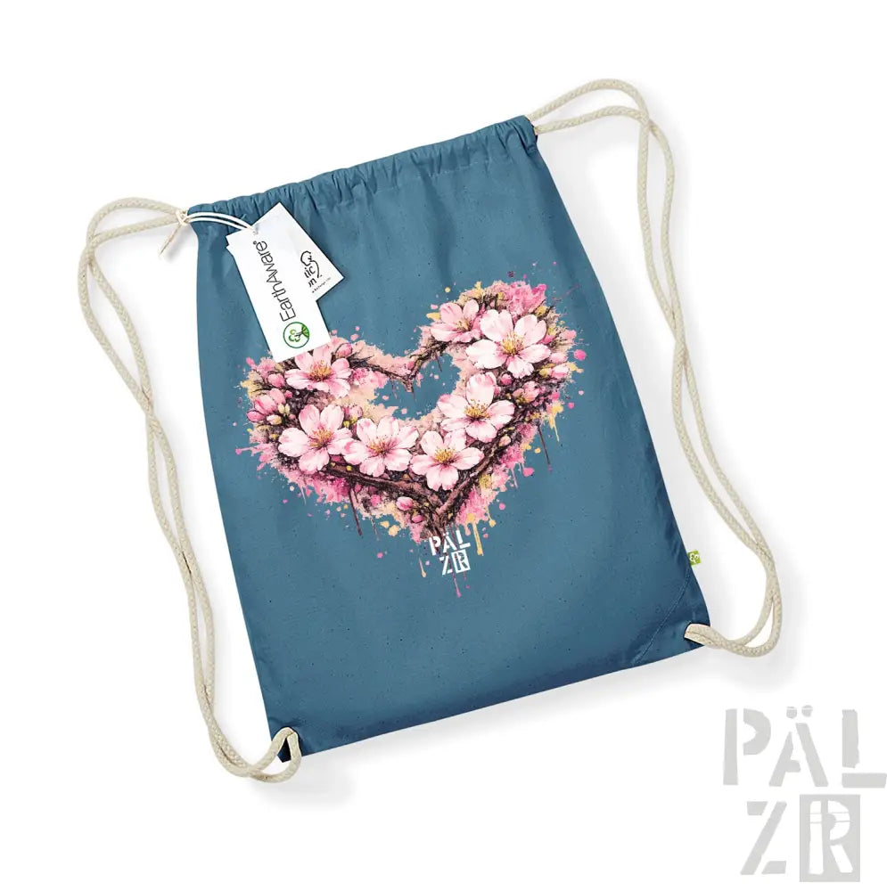 Eine türkisfarbene Beutel mit Kordelzug, die ein lebendiges, pinkfarbenes Kirschenblüten-Herz-Design mit Spritzeffekten und dem Text „pal zib“ darunter zeigt.