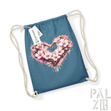 Eine türkisfarbene Beutel mit Kordelzug, die ein lebendiges, pinkfarbenes Kirschenblüten-Herz-Design mit Spritzeffekten und dem Text „pal zib“ darunter zeigt.