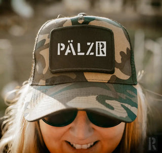 Camo-Trucker-Cap mit ’palzr’-Patch, schwarzes und grünes Tarnmuster, Mesh-Rückseite, verstellbarer Riemen.