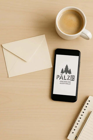 Ein schwarzes Smartphone zeigt ein Logo mit drei immergrünen Bäumen und dem Text »PÄLZR«.