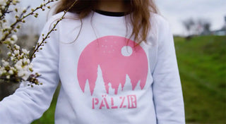 Ein weißes langärmeliges Sweatshirt mit einem pinken grafischen Design.