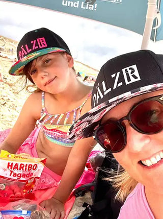 Zwei Personen tragen passende Baseballmützen mit ‚PÄLZR‘